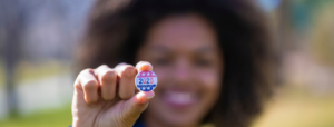 Girl holding up a pin that says 2020
